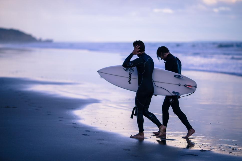 two surfers wearing wetsuit at the beach
